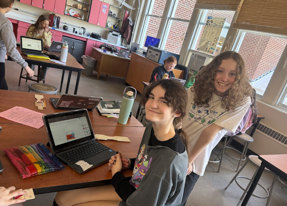 two students smiling working on coding on their chromebook