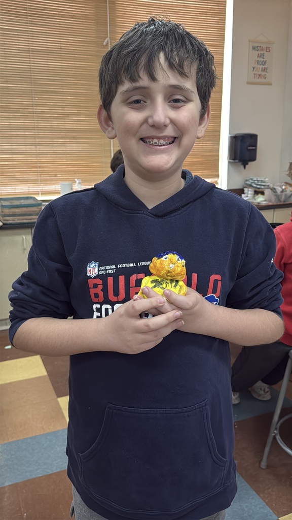 student holding their prized art work, smiling