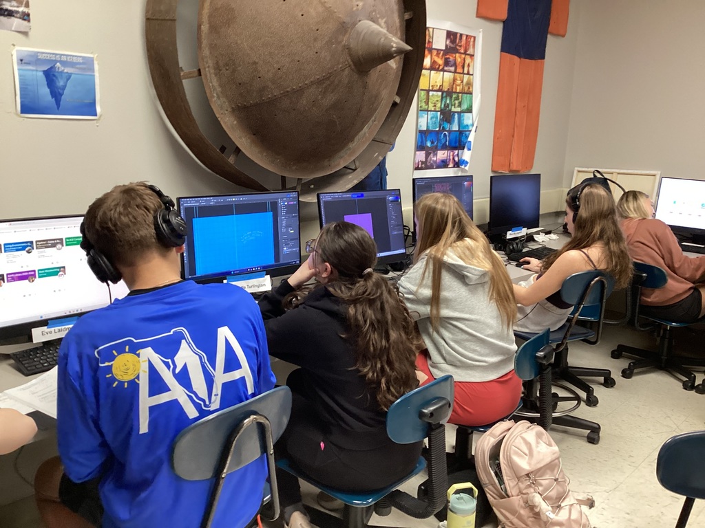 Highschool students working on their personal yearbooks on computers