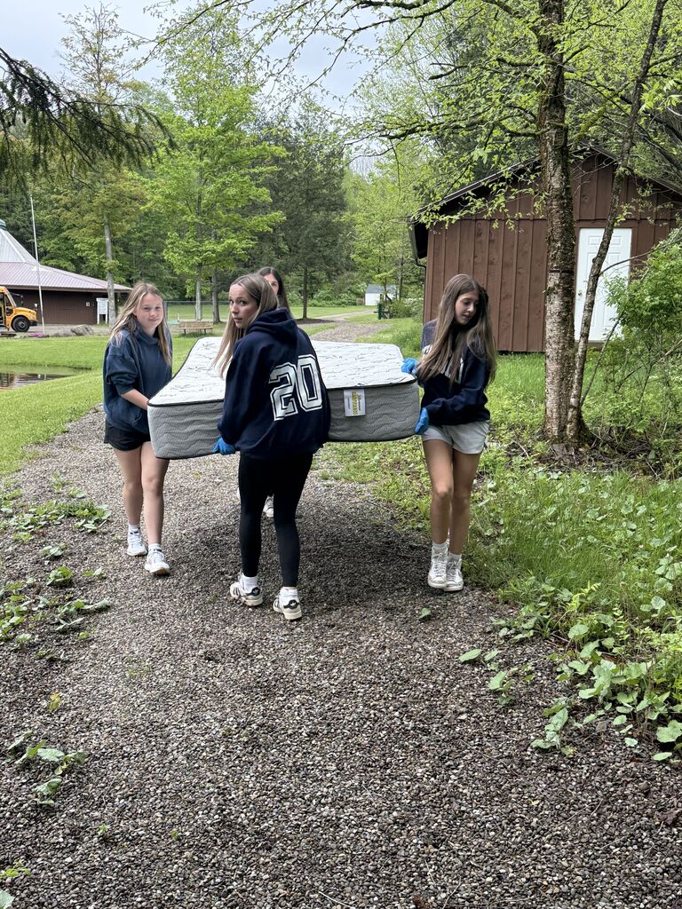 students completing service learning by carrying a matress to an air b and b