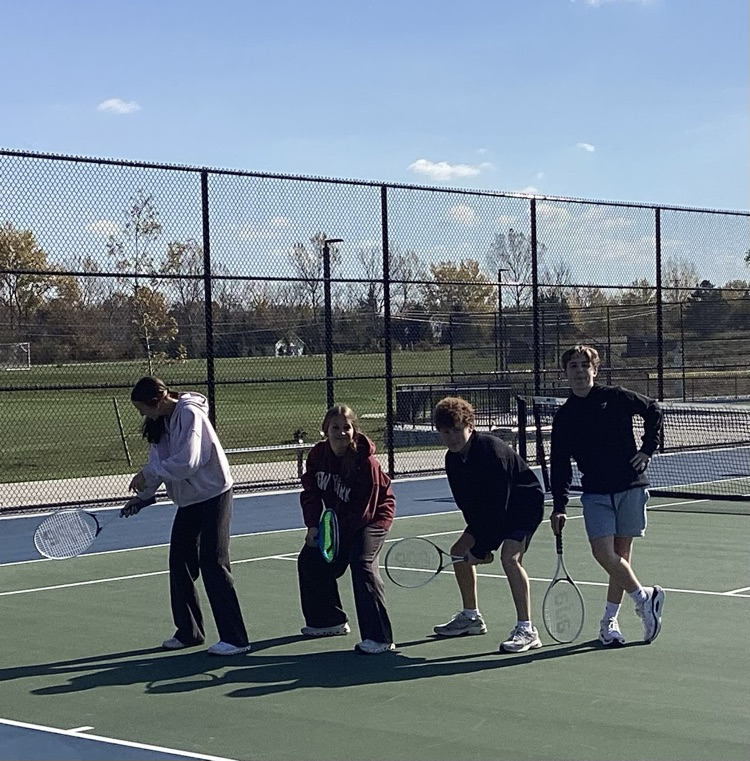 four students posing in tennis courts