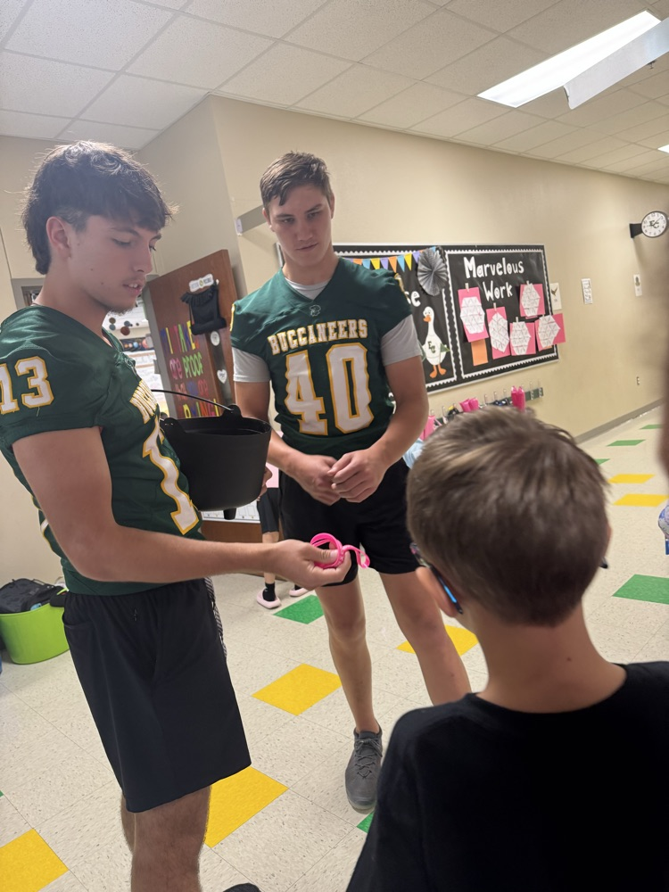 Varsity Football Players presenting PINK OUT bracelets to students
