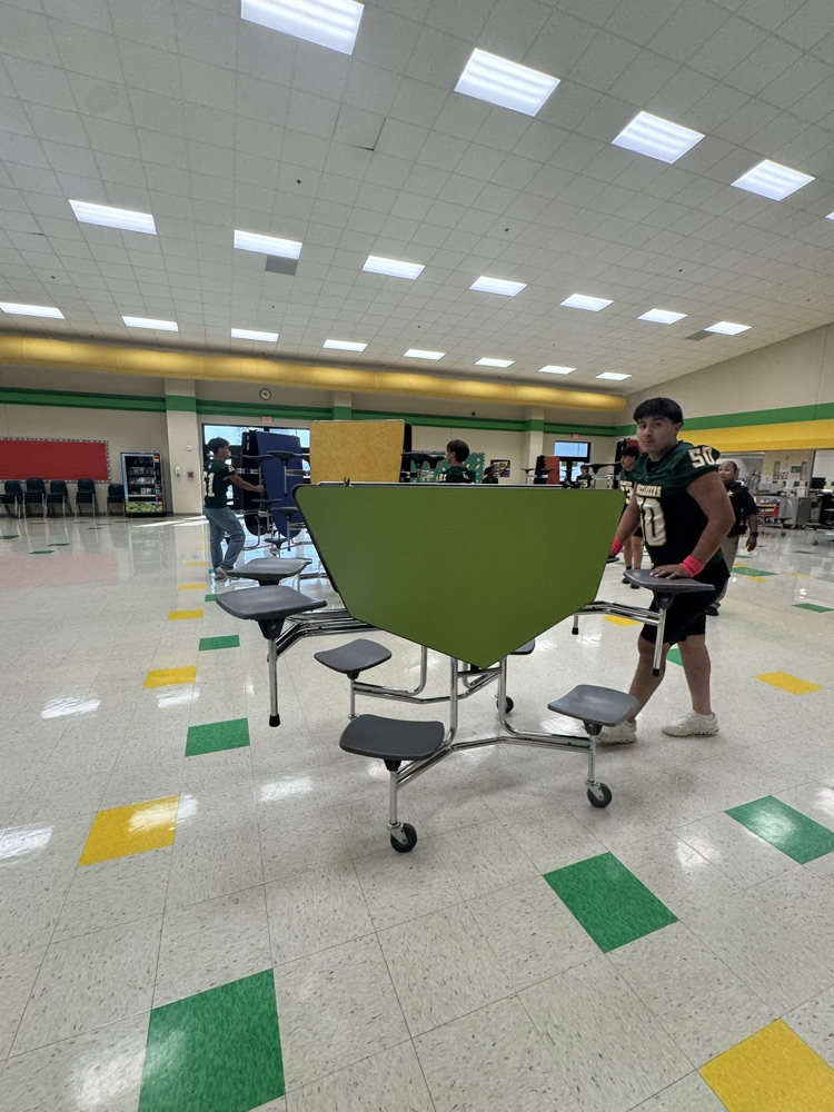 football players helping put tables back after Fantastic Friday