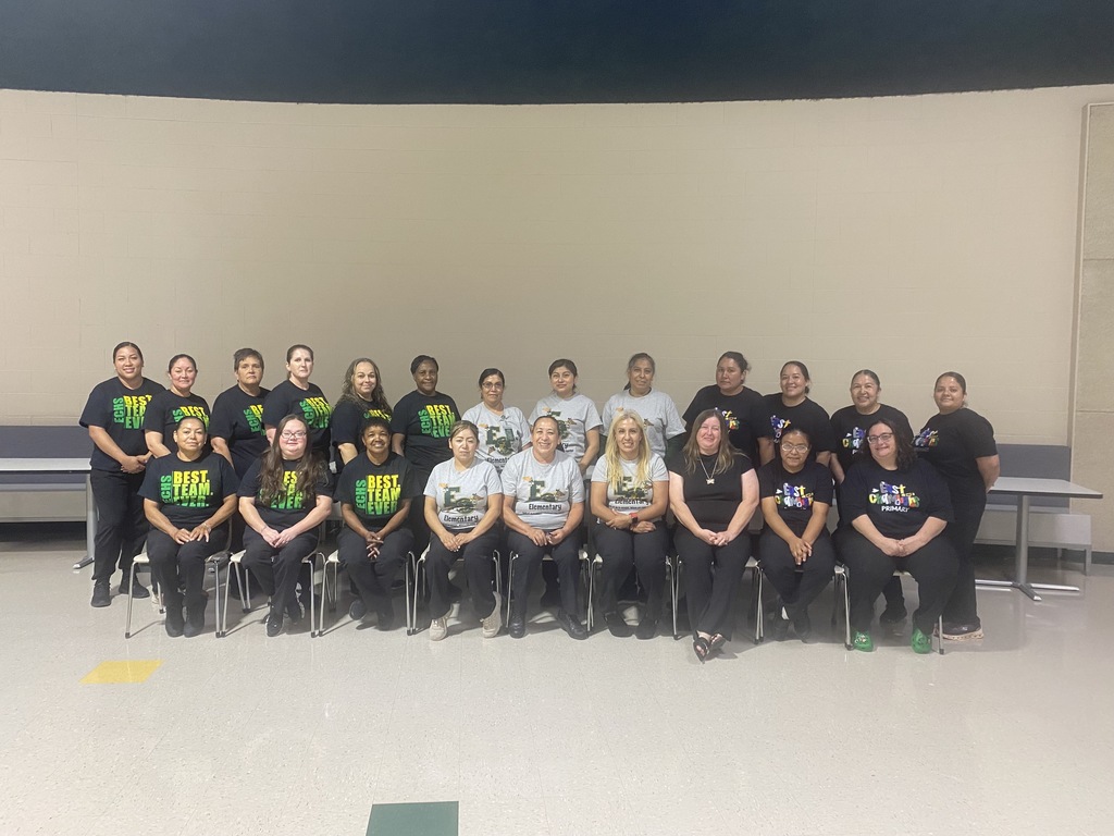 A group of people in matching shirts and pants pose for a photo in a room.