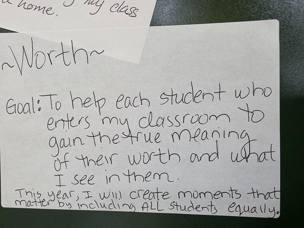 Handwritten text on white paper displays educational goals. It reads, "To help each student gain the true meaning of their worth." Below, it adds, "I see in them."