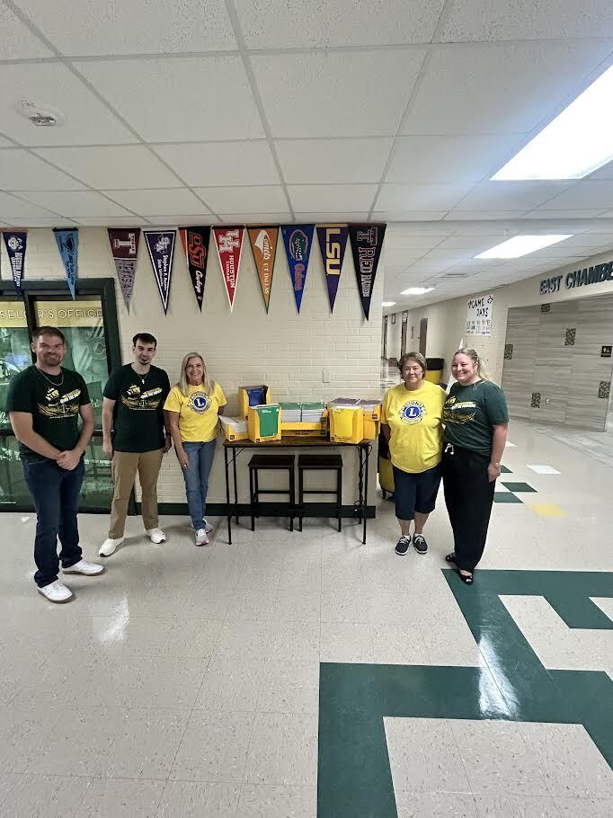 Staff members accepting school supplies from Lion's Club representatives.