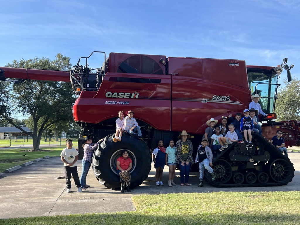 Several children and adults stand around a large red tractor. The tractor is labeled "CASE IH" on the front.