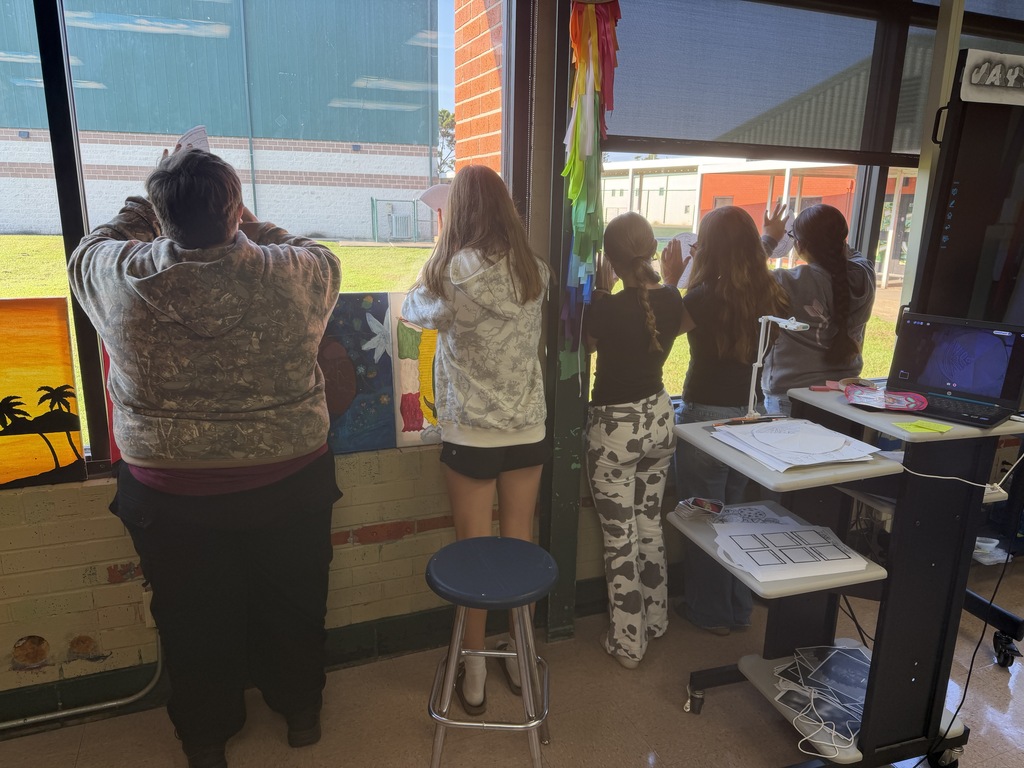 A group of students standing in a classroom, observing a colorful artwork on the wall.