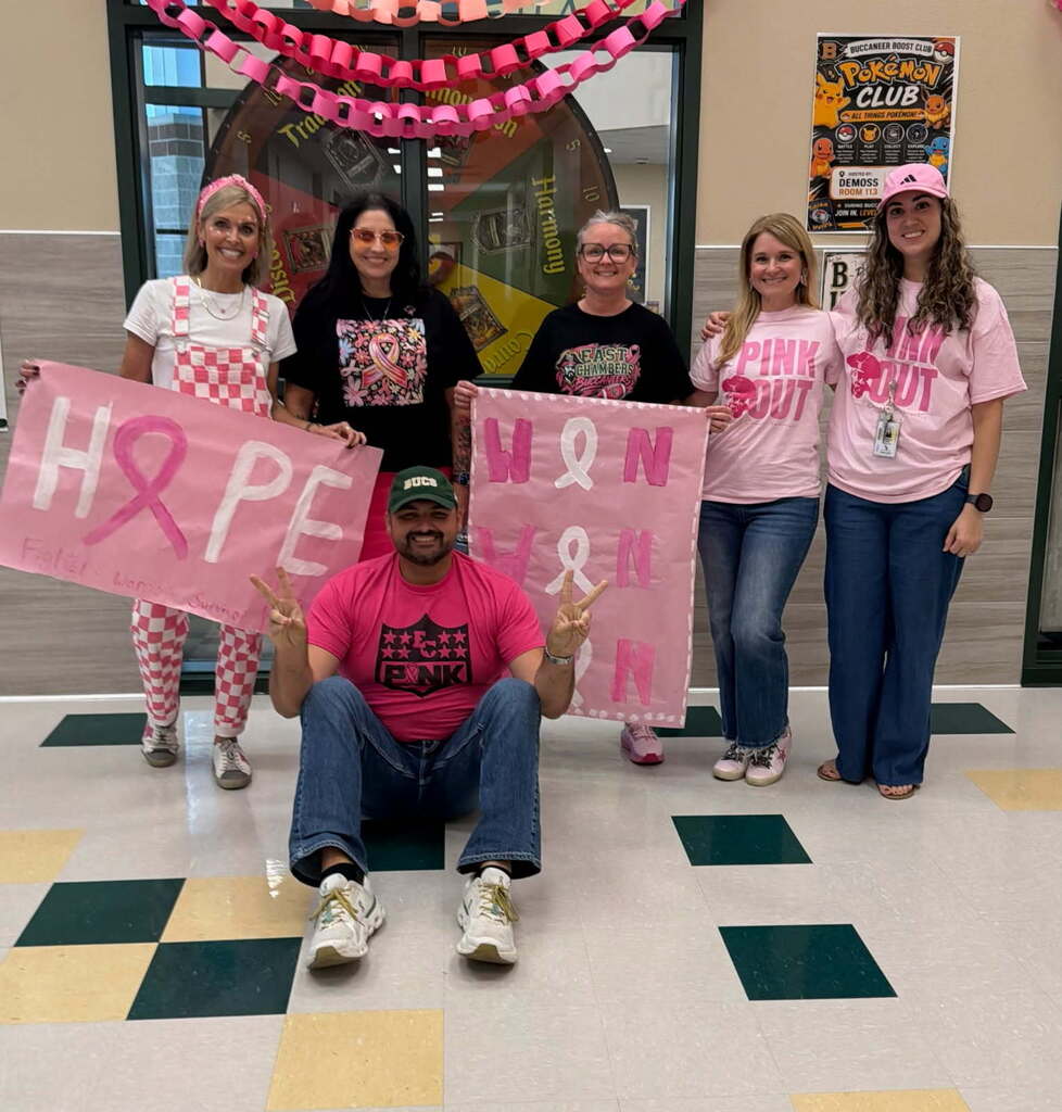 Five people in pink T-shirts stand in a hallway. One person crouches and holds a banner that says "HOPE".