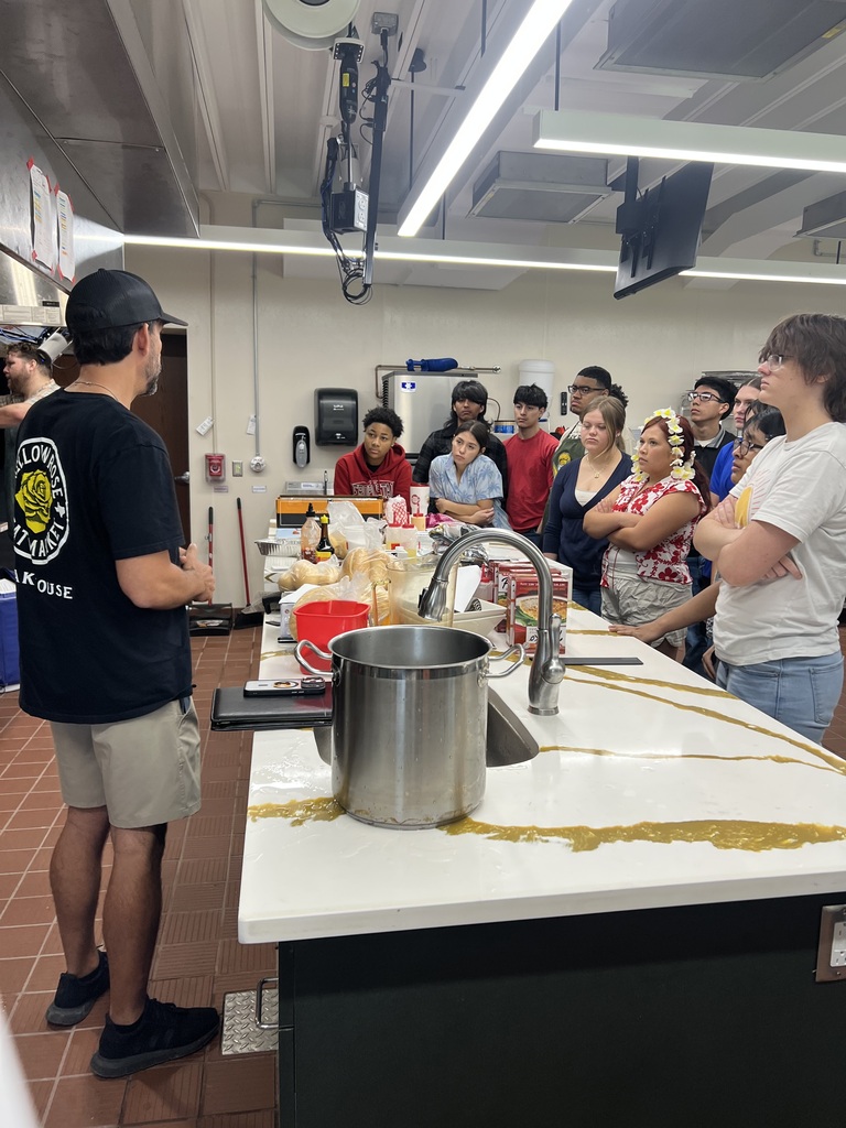 A group of people are gathered in a kitchen, with one person standing by a sink.