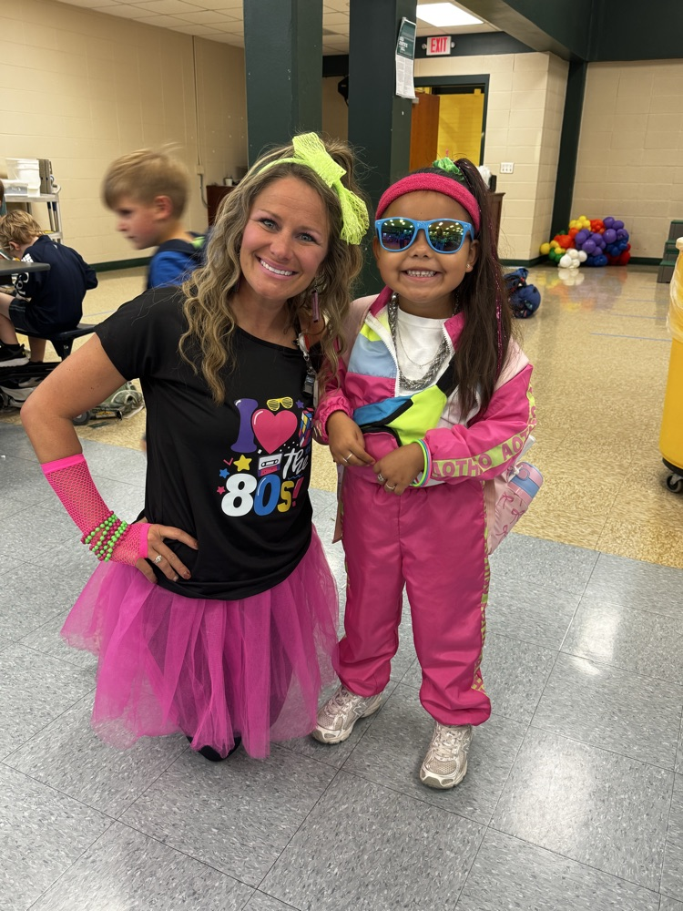 A woman and child dressed in pink, yellow, and white costumes are smiling and posing for a photo.