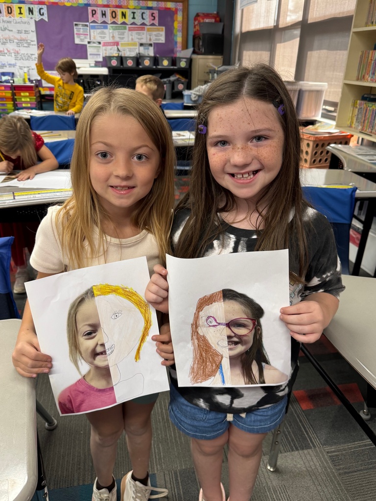 Two second grade girls showing off their self portraits