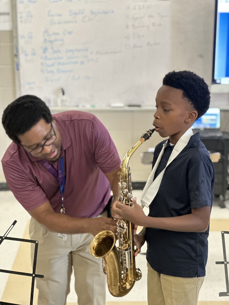 A teacher assists a student playing saxophone.