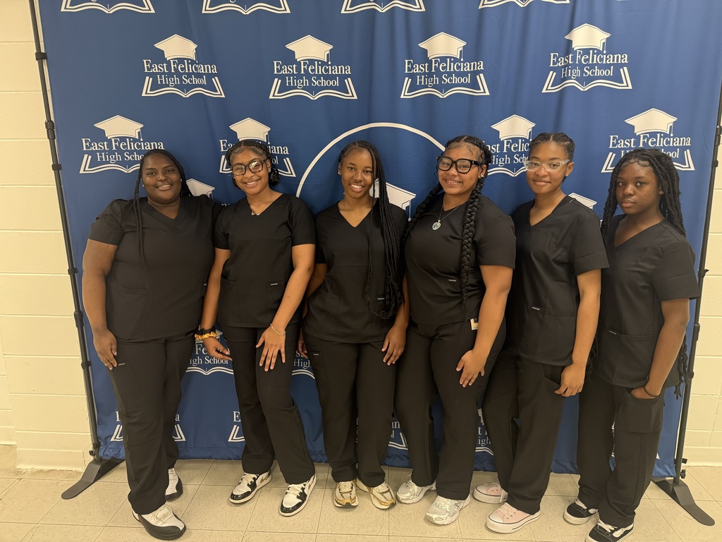 a group of six students in scrubs in front of a banner.