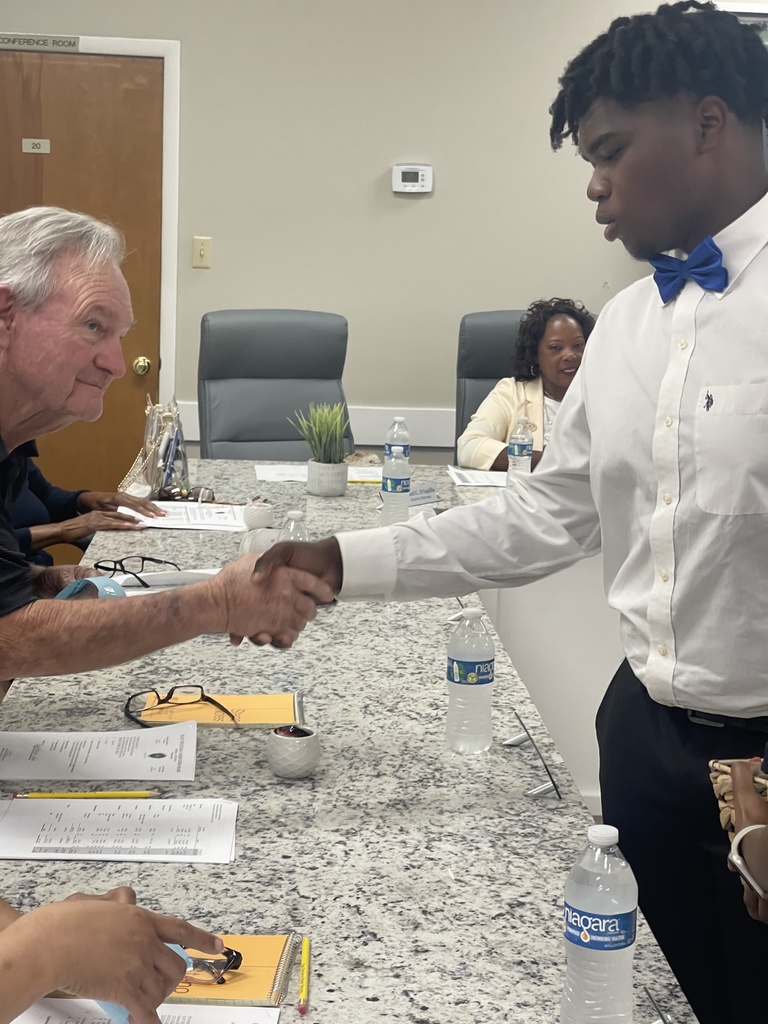 A student shakes an adult's hand.