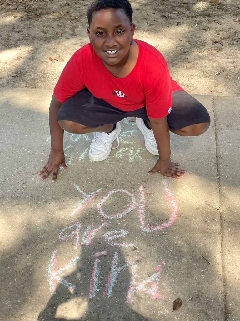 Student with a chalk message that says "you are kind."