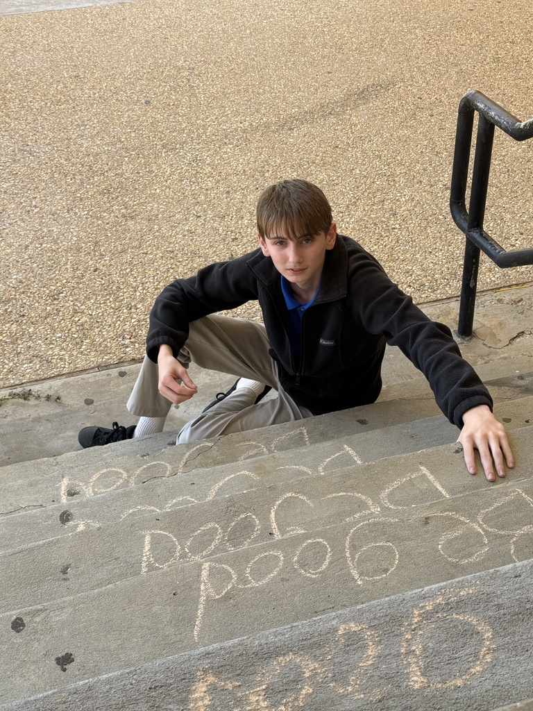 Student writes a chalk message that says 'be good."