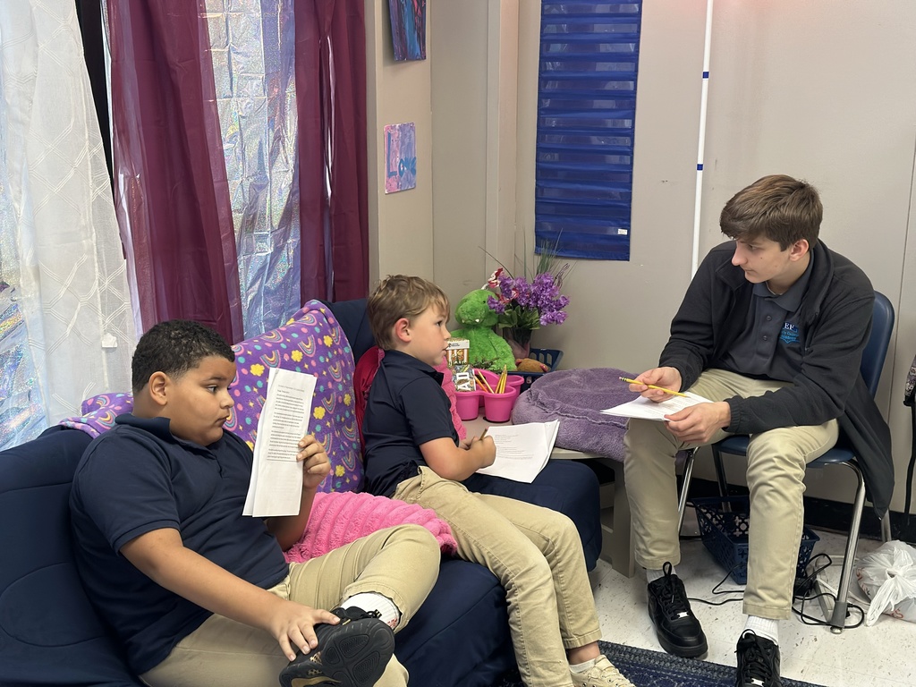 A high school student tutors two elementary students.