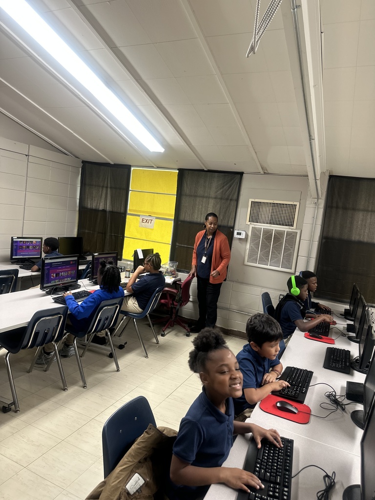 Students working on computers with the support of a para educator.