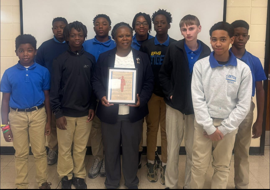 A group of students with a teacher holding a plaque.