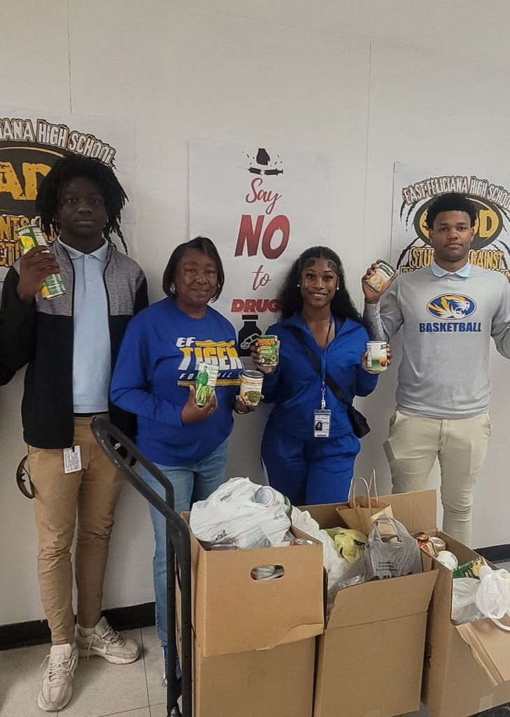 Students and a teacher holding food from a can drive.