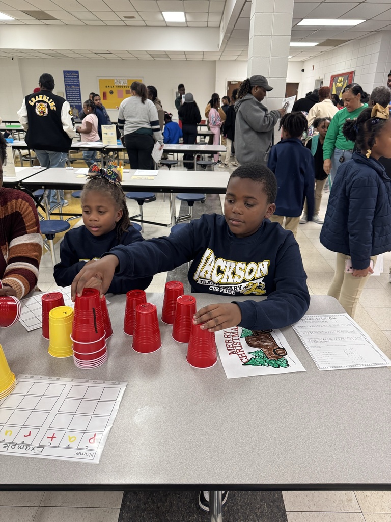 Students participate in literacy night with families in the background.