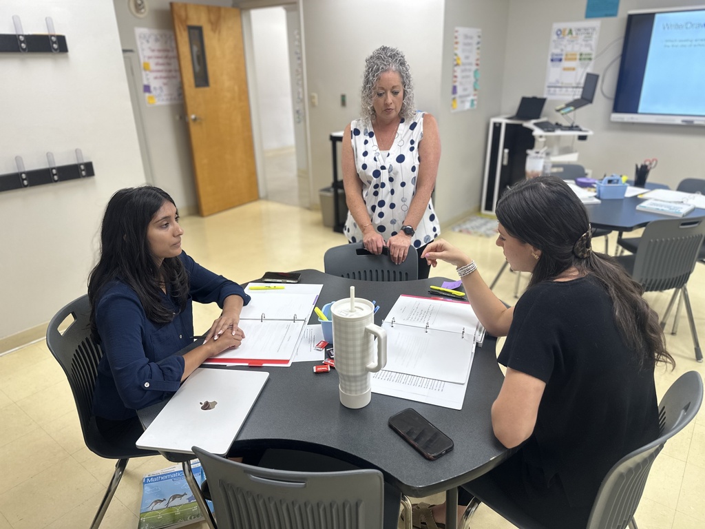 Two new teachers talking while someone watches.