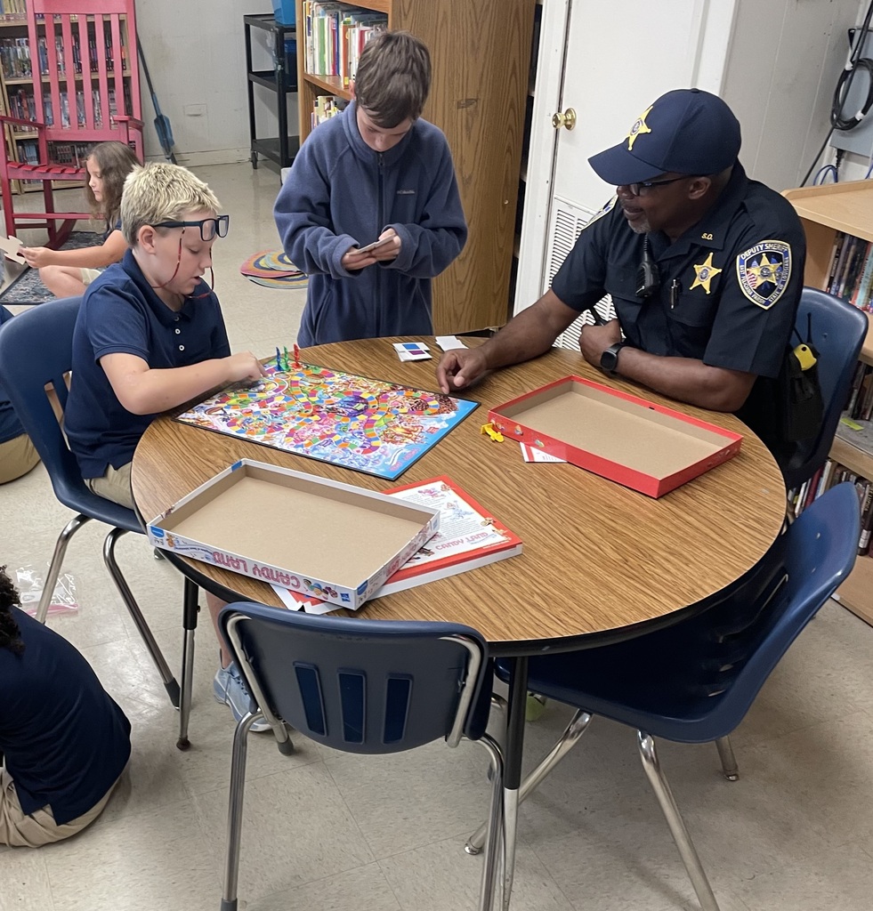 A school resource officer plays a game in a library with children.