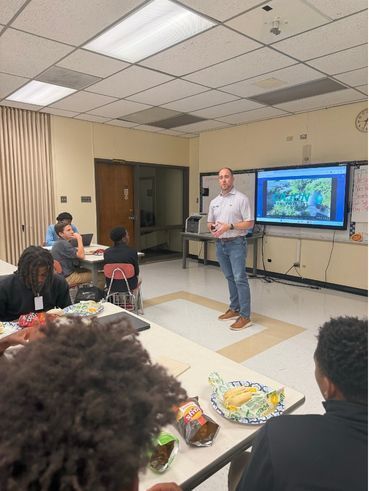 A person talks to a group of students in a classroom.