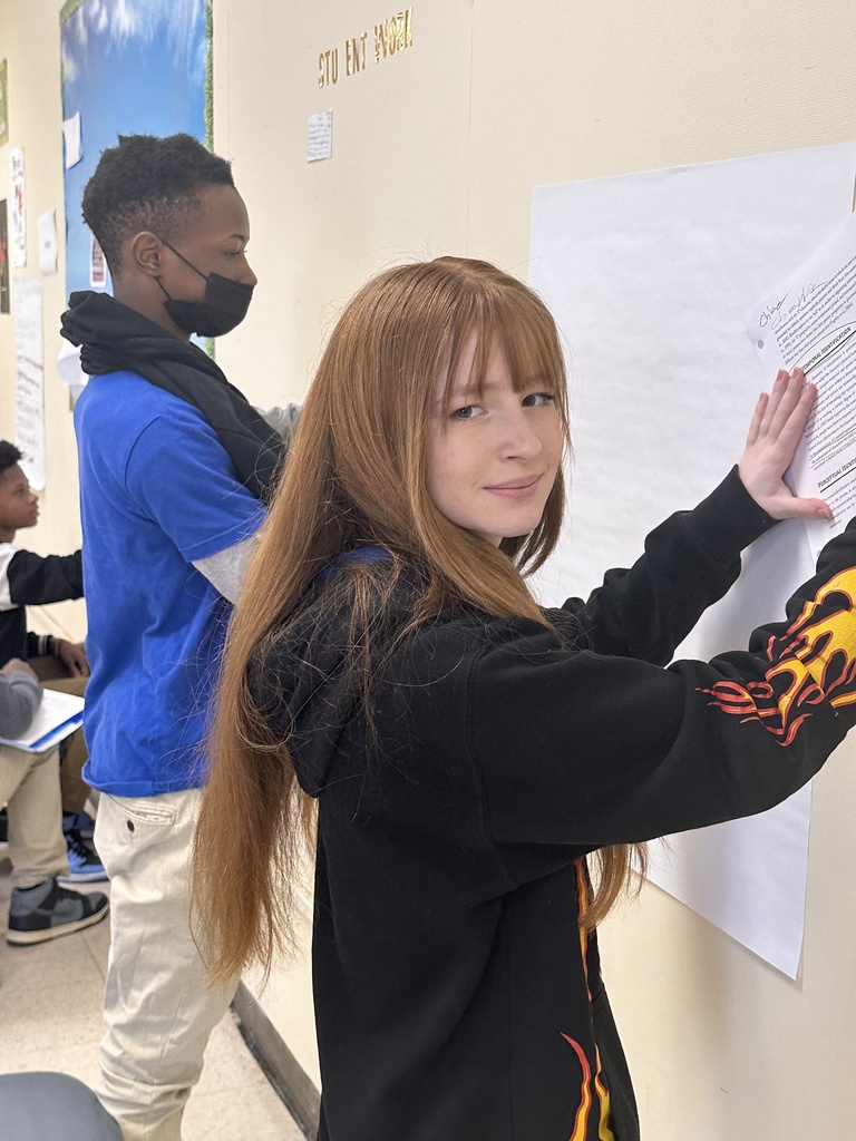 Two students writing on chart paper.