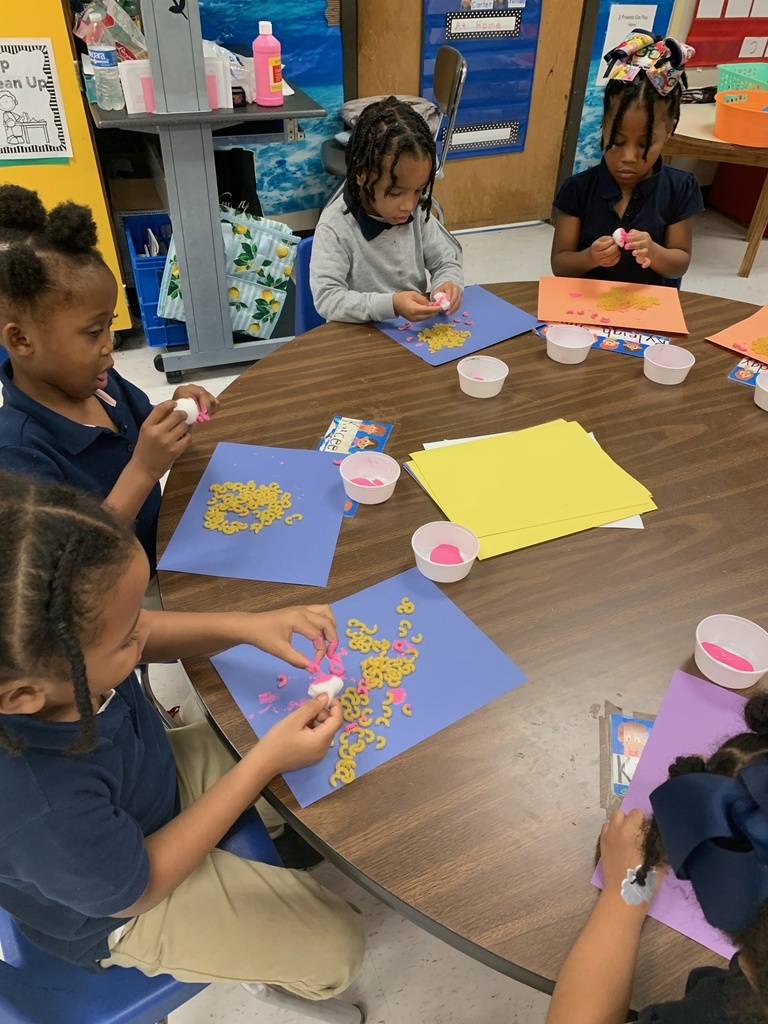 Students at a table making macaroni art.