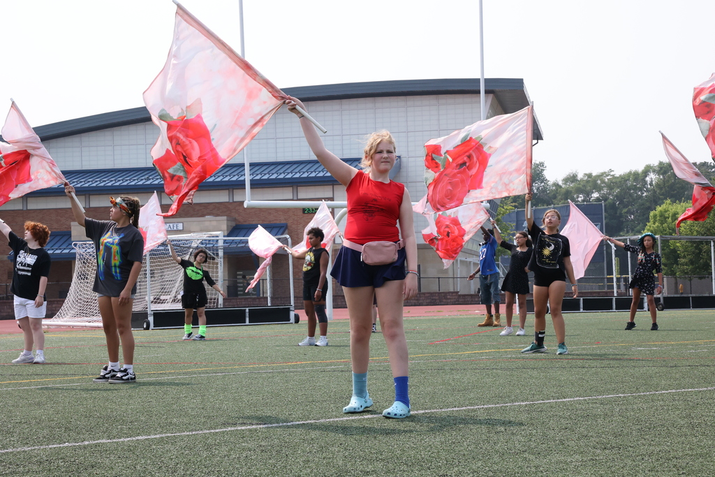 Flag dancers prepare their routine during the lancer band camp holding rose flags