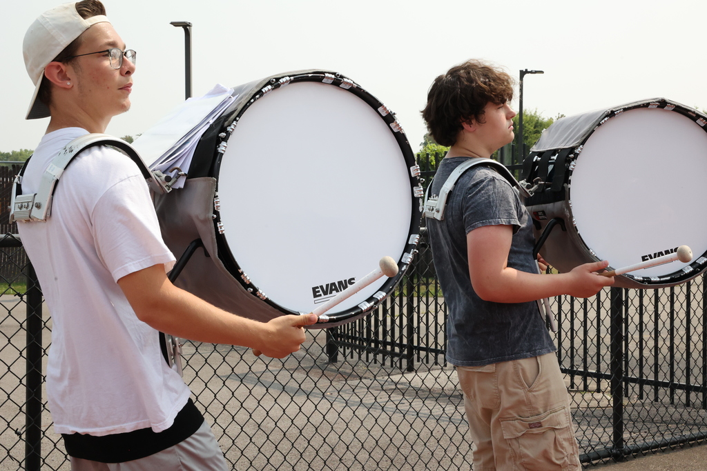 students in drumline practice their part, two drummers hold their mallets and drums