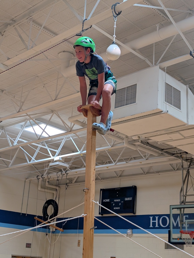 Student stands on wood structure with green helmet