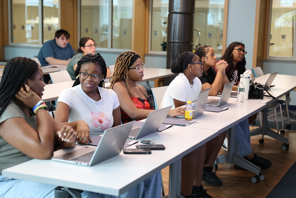 students listen with laptops while sitting at table