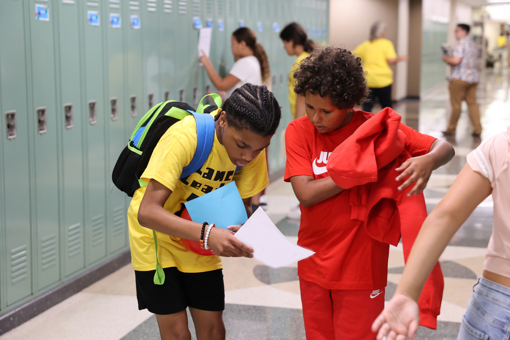 Two students look at their schedules in the hallway