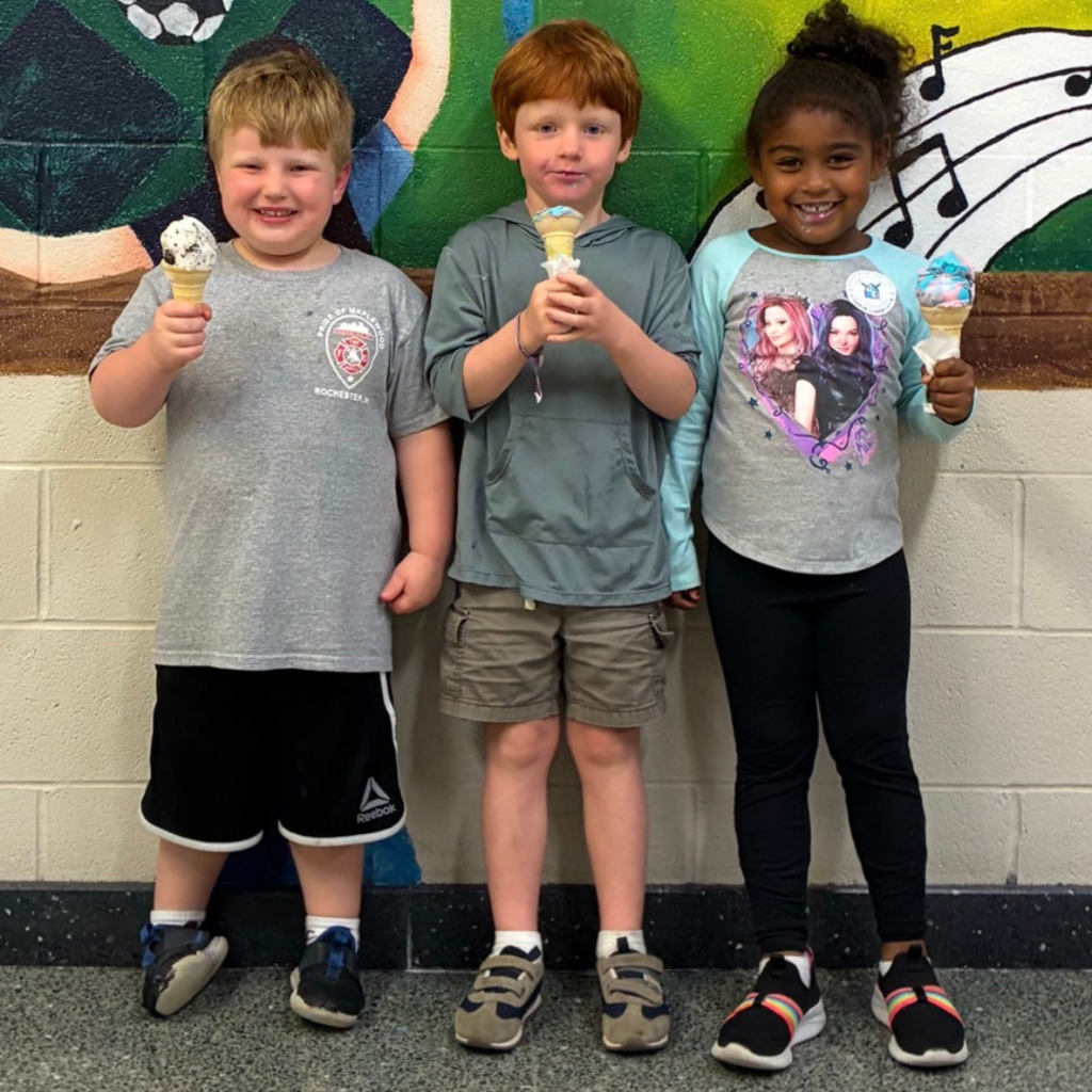 3 students smile with icecream cones at a school event