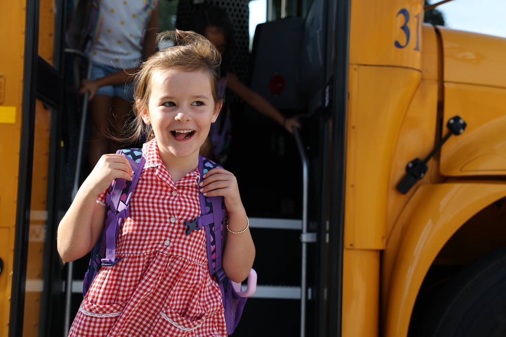 Student jumps off the bus excited with her backpack