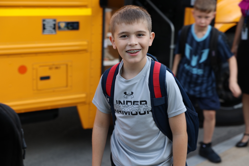 student smiles as he gets off the bus