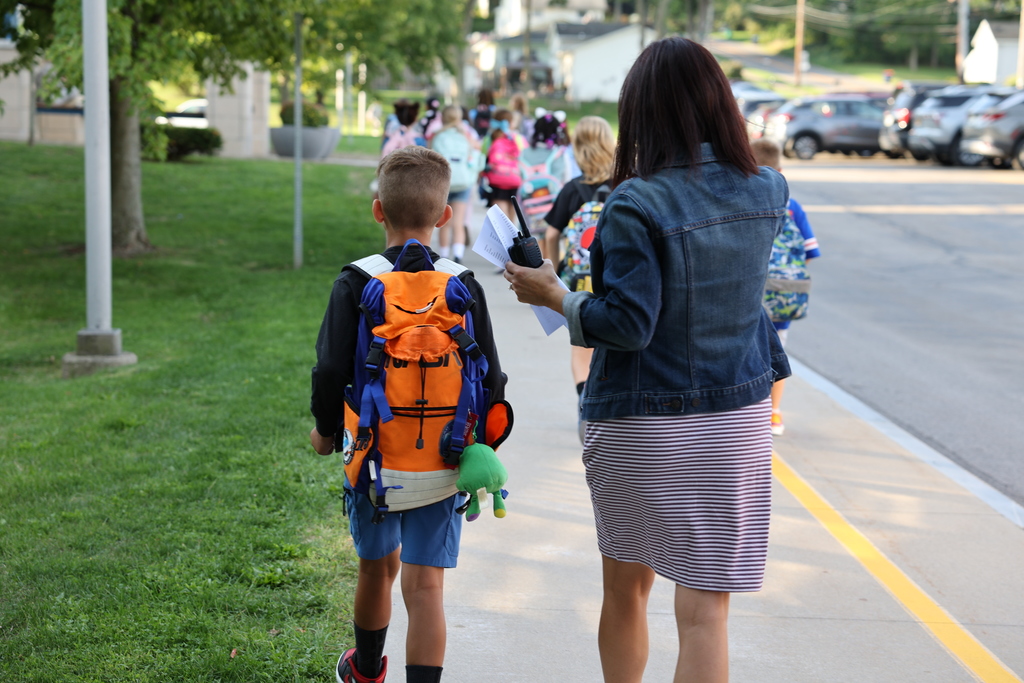 student walks with staff member to the building