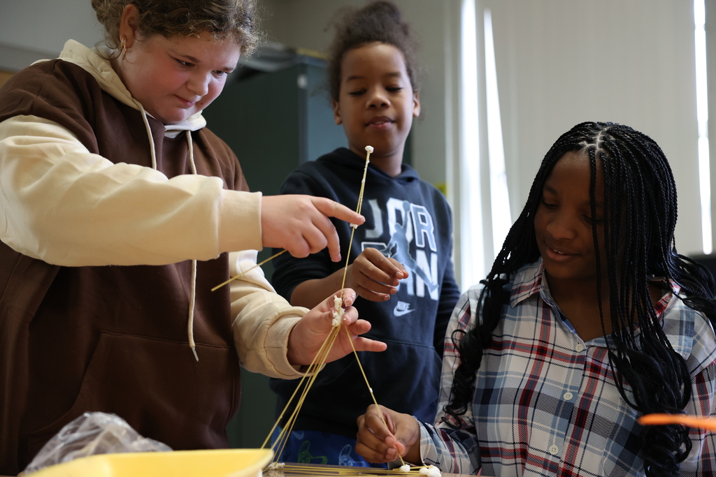 Students steady a piece of spaghetti from falling from their tower
