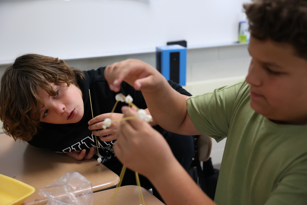 Student examines the tower creation he is building with his partner
