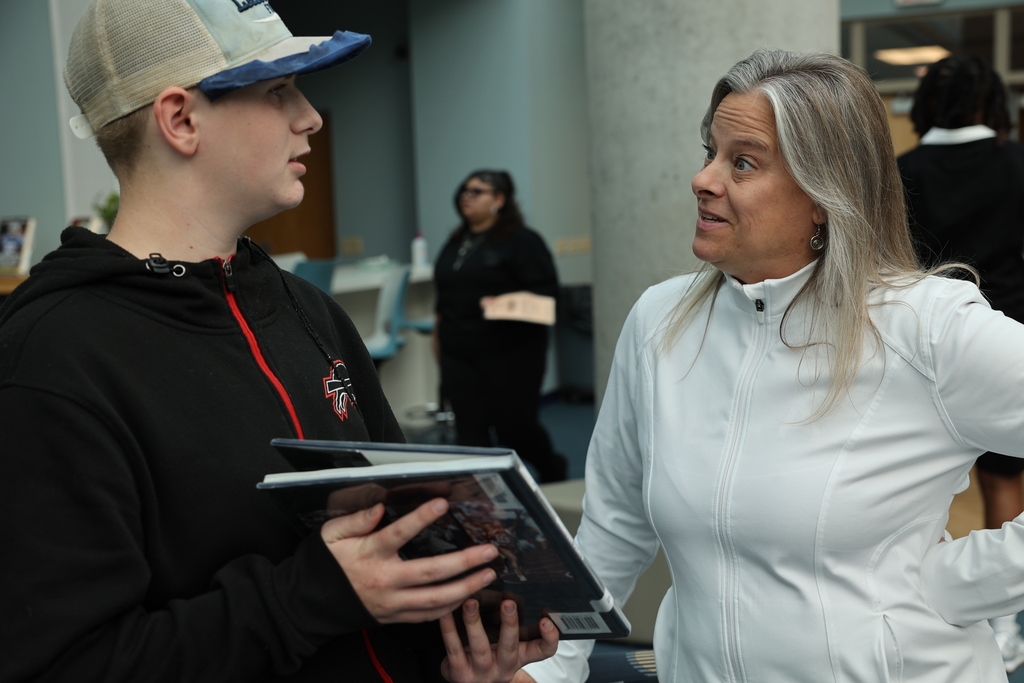 Students shows librarian the book he chose 