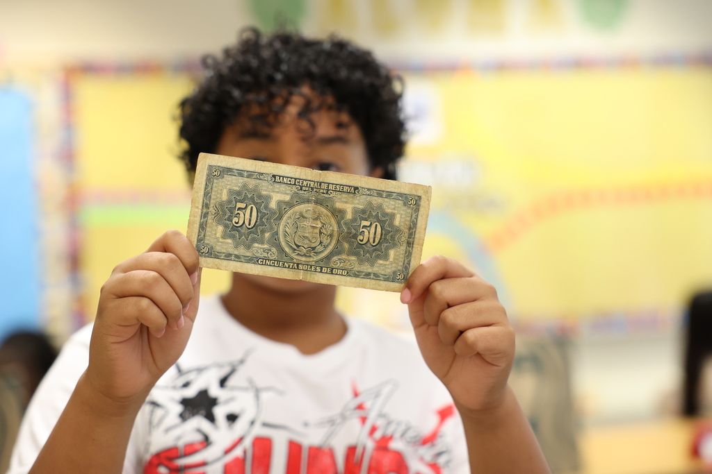 student holds up 50 dollar bill from another country