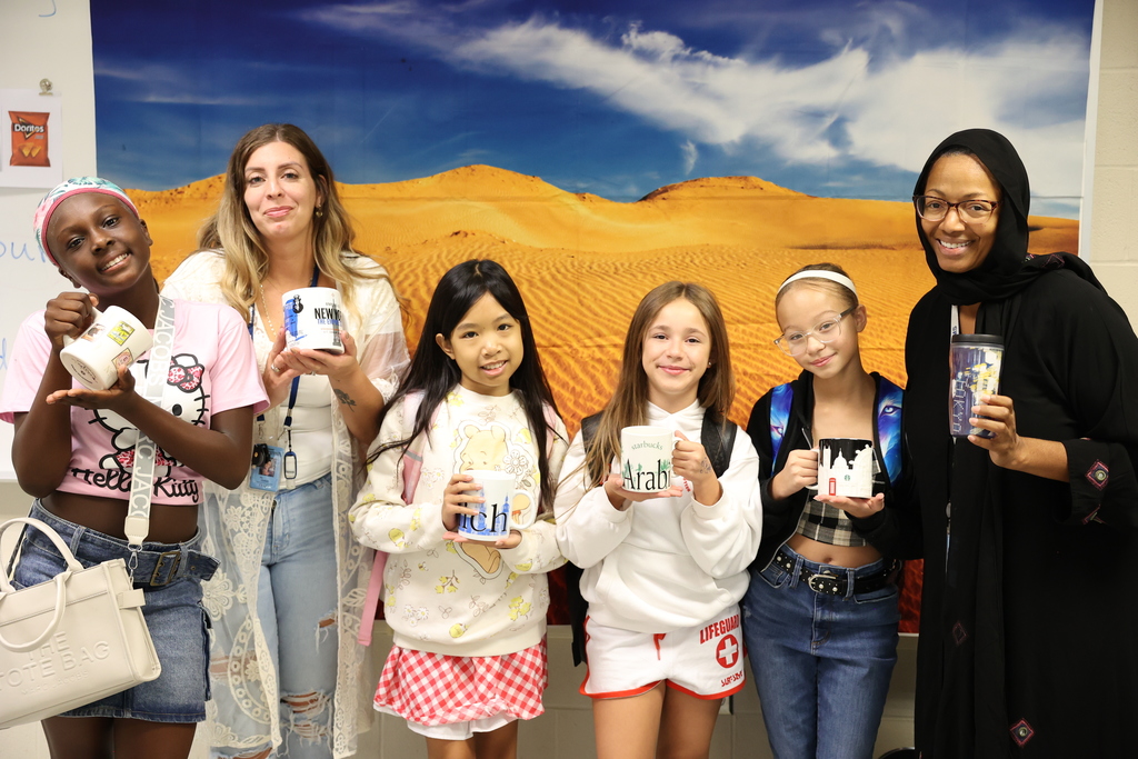 Students hold up starbucks mugs from all over the world