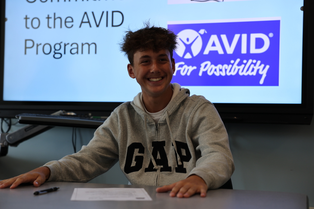 Student signs and smiles AVID contract