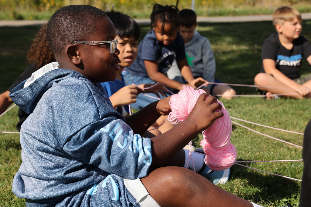 Student talks while hold pink yarn ball