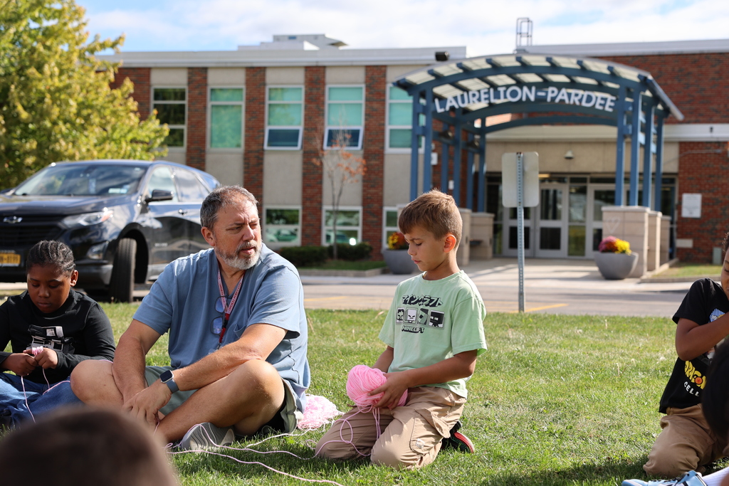 Mr. Dejohn and student sit and talk with yarn in student's hands