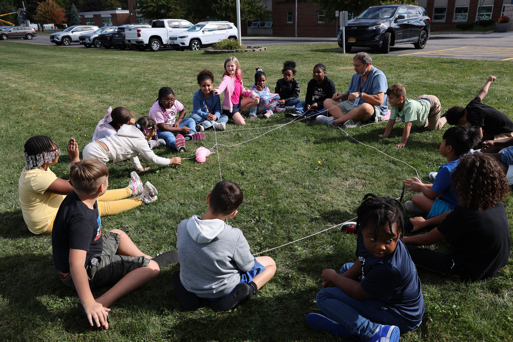 Students sit in a circle with yarn