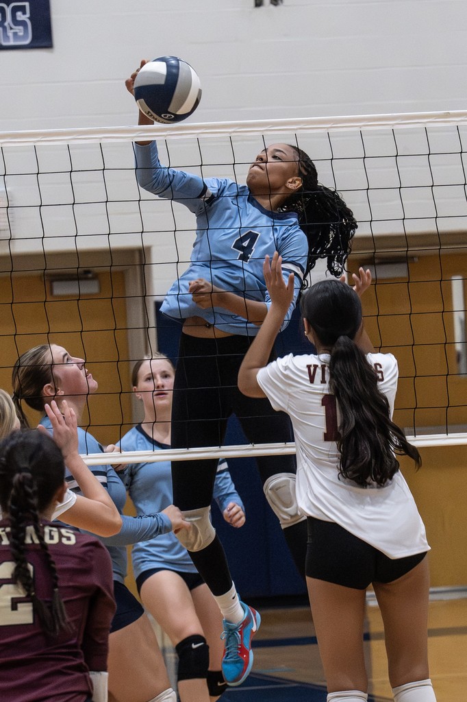 Volleyball player spikes the ball over the net